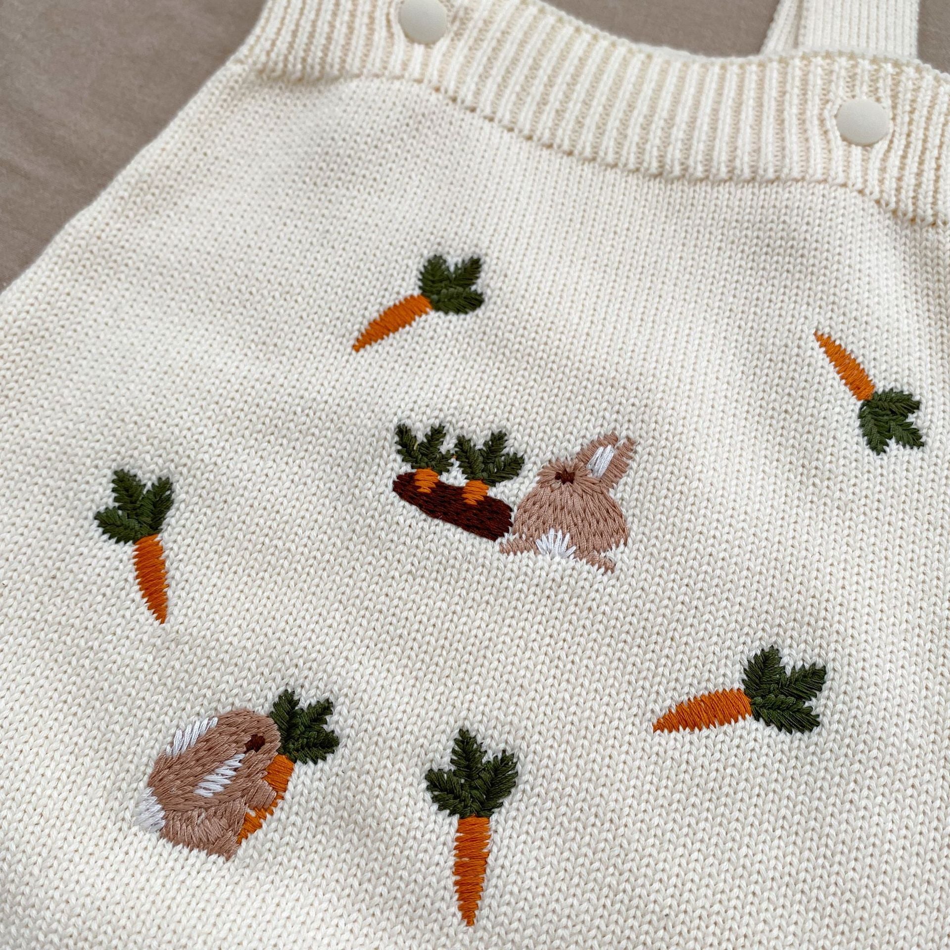 A beige and apricot long-sleeve baby outfit featuring cute cartoon rabbits embroidery, perfect for autumn wear.