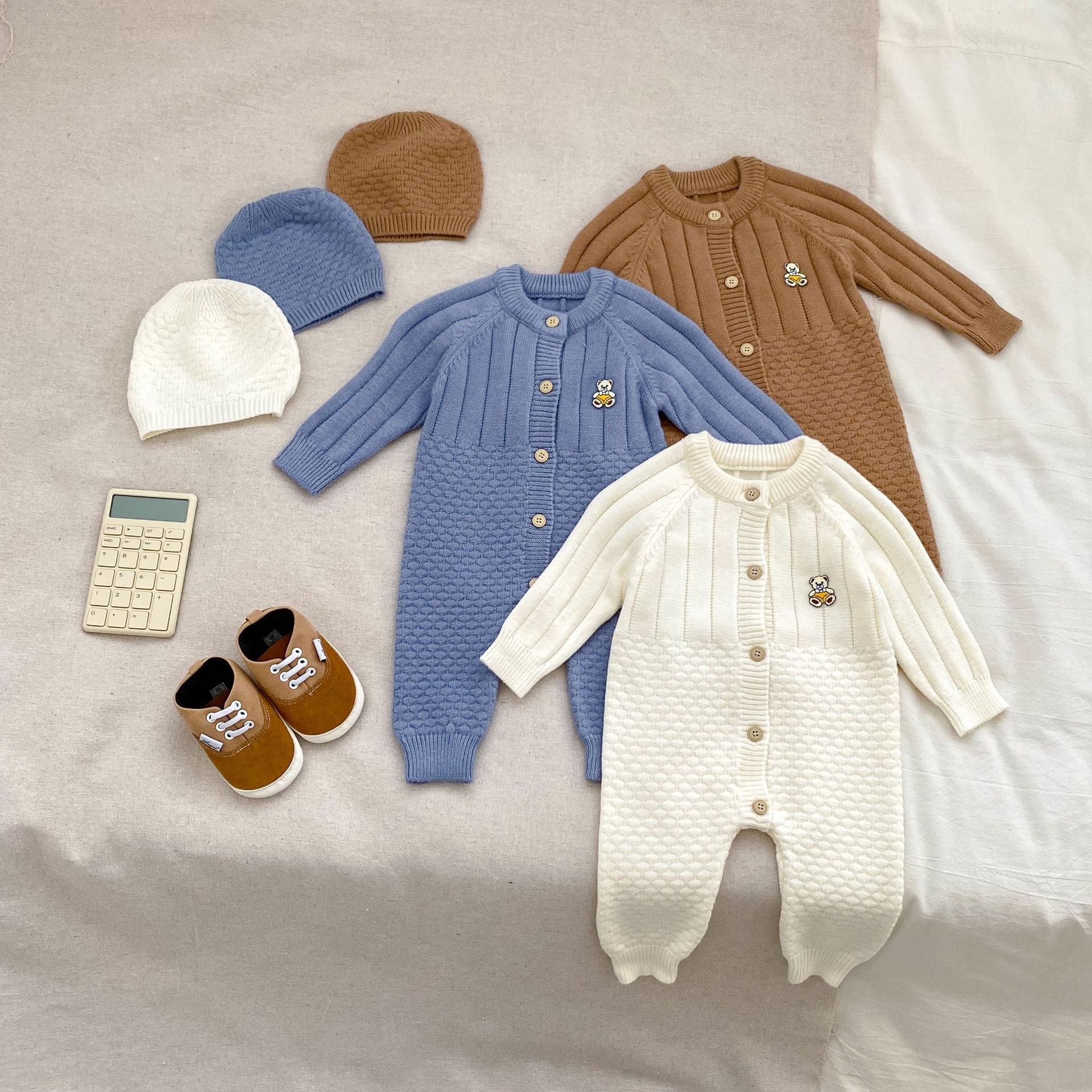 A cozy knitted romper for babies featuring a teddy pattern, available in blue, apricot, and coffee colors, perfect for autumn and winter.