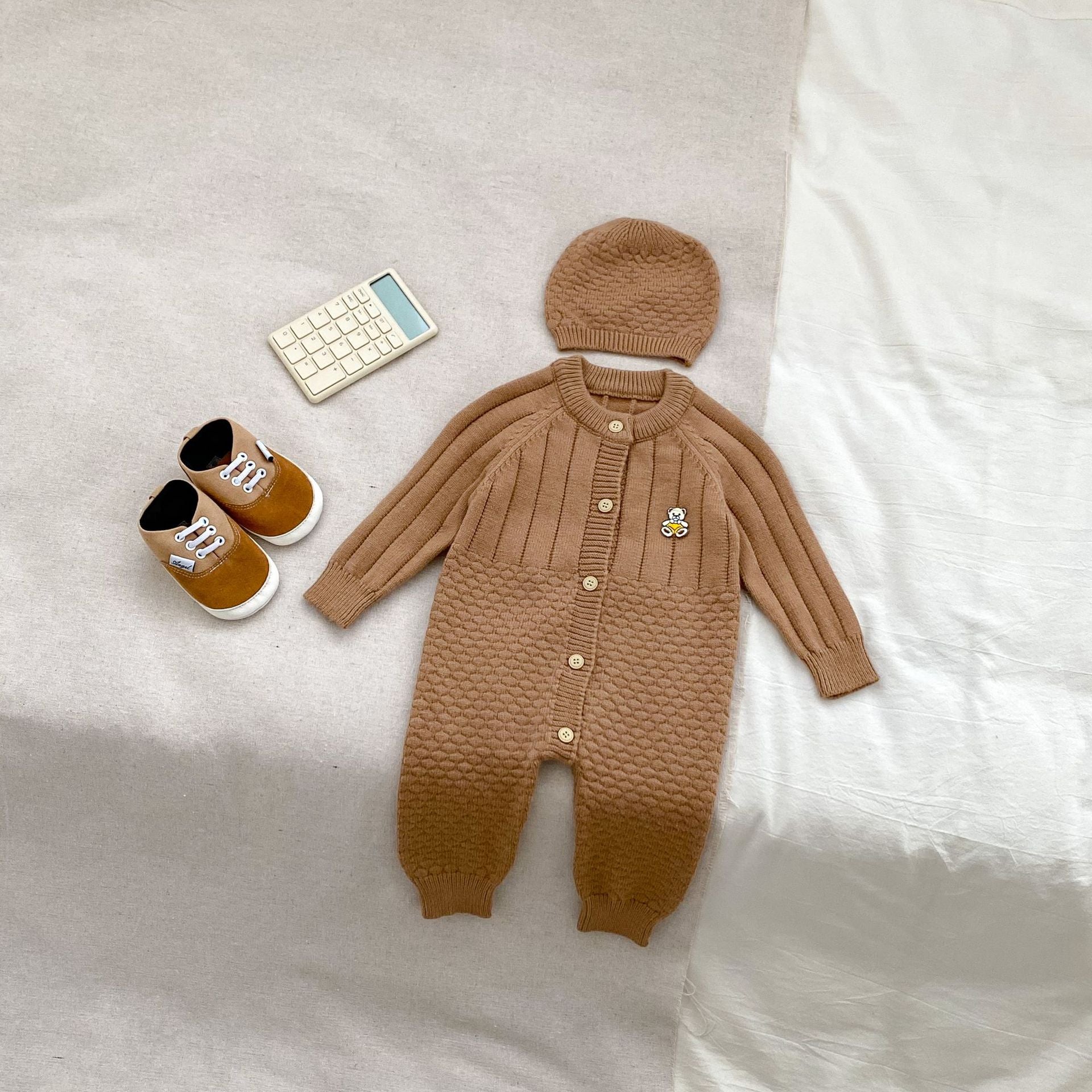 A cozy knitted romper for babies featuring a teddy pattern, available in blue, apricot, and coffee colors, perfect for autumn and winter.