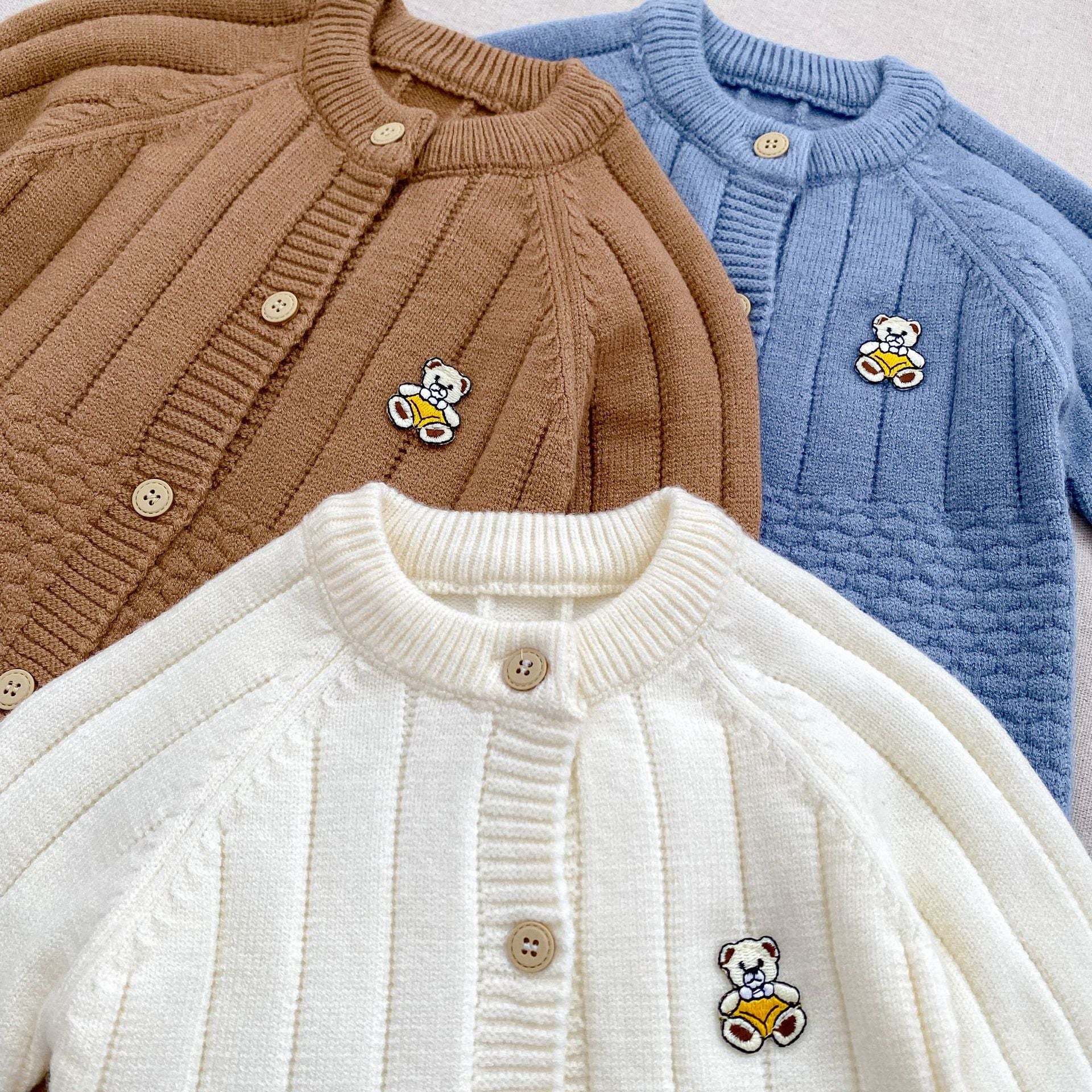 A cozy knitted romper for babies featuring a teddy pattern, available in blue, apricot, and coffee colors, perfect for autumn and winter.