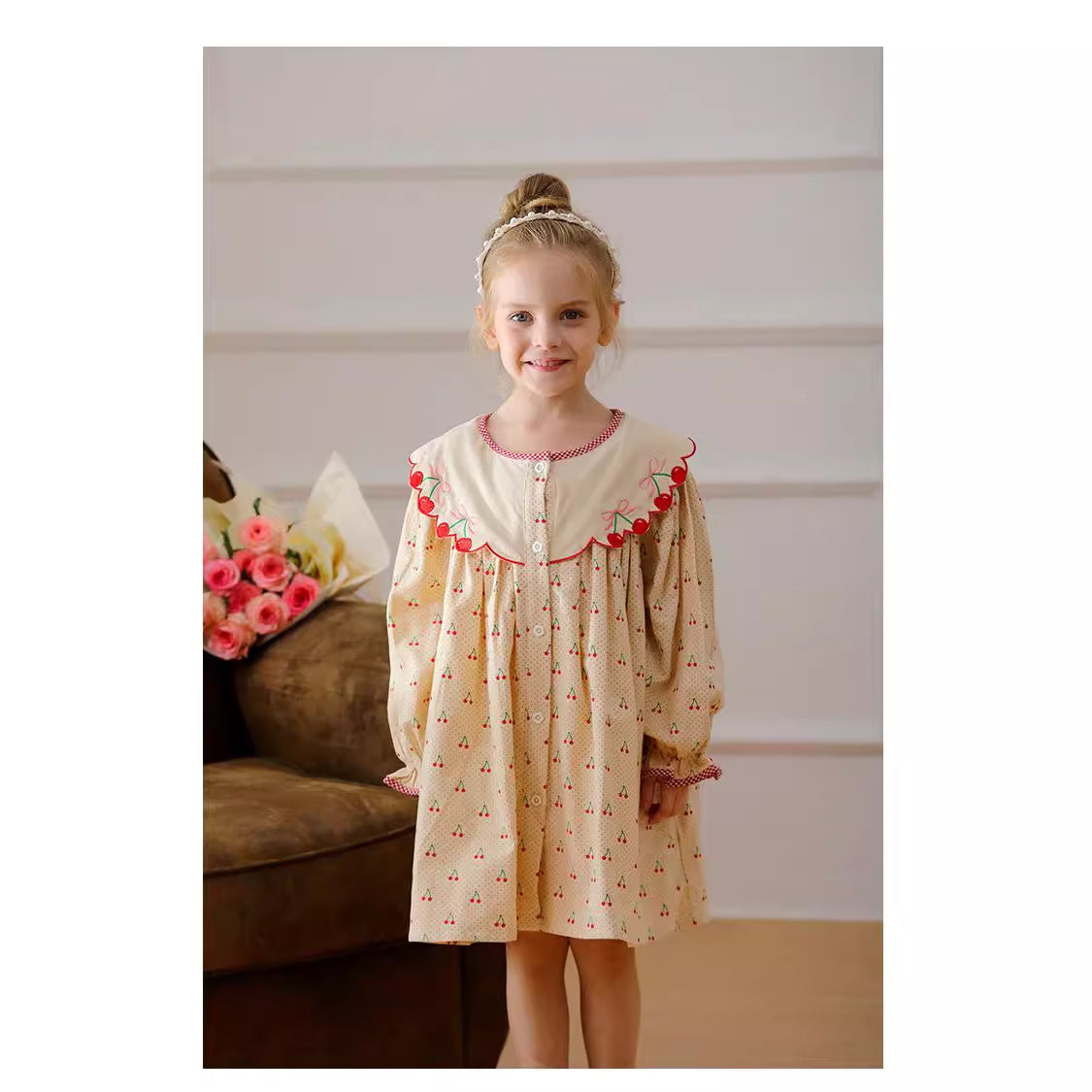 A charming long-sleeved dress for girls featuring a playful cherry pattern, made from soft cotton in apricot color.