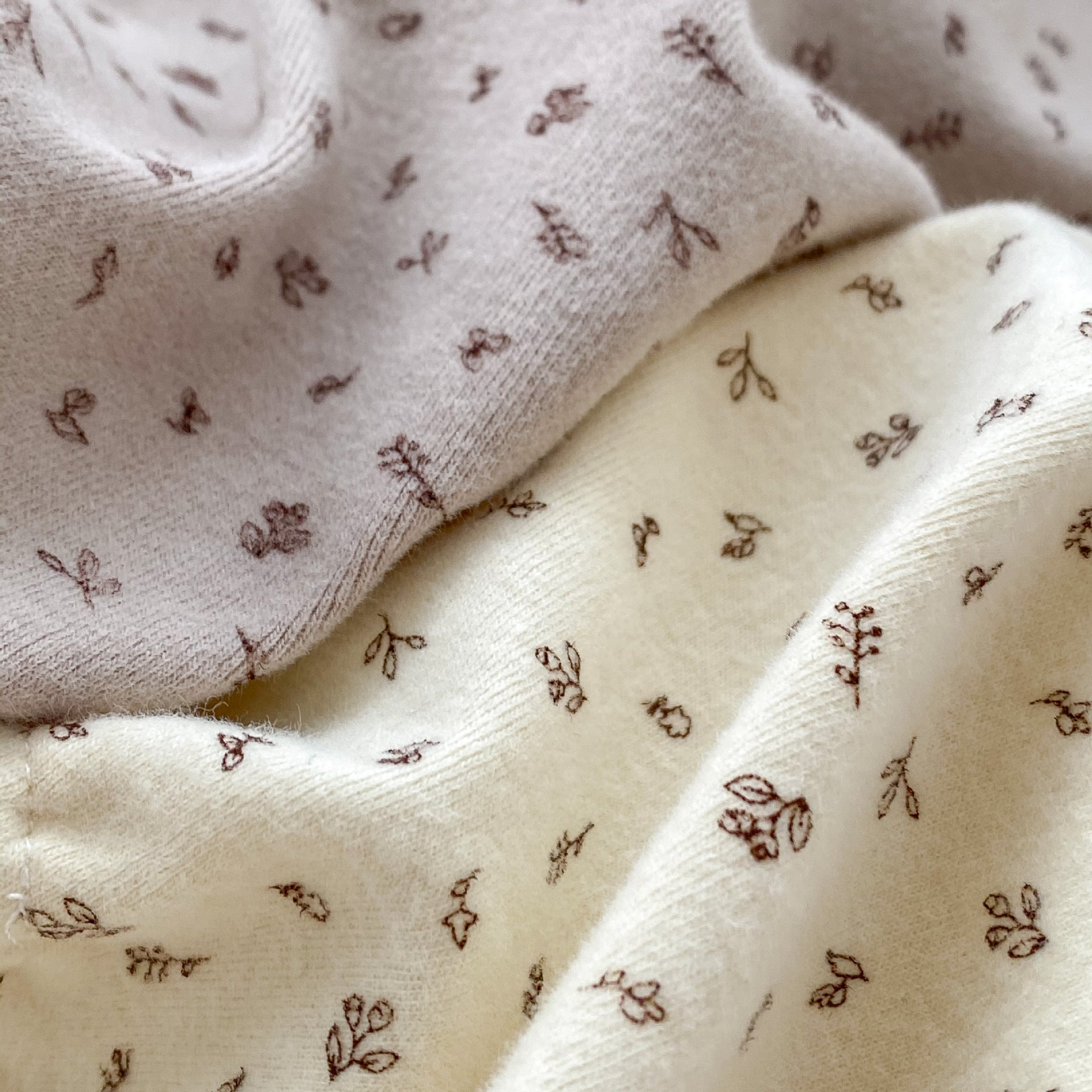 A baby girl wearing a floral print ruffle collar onesie in grey, showcasing long sleeves and a charming design.