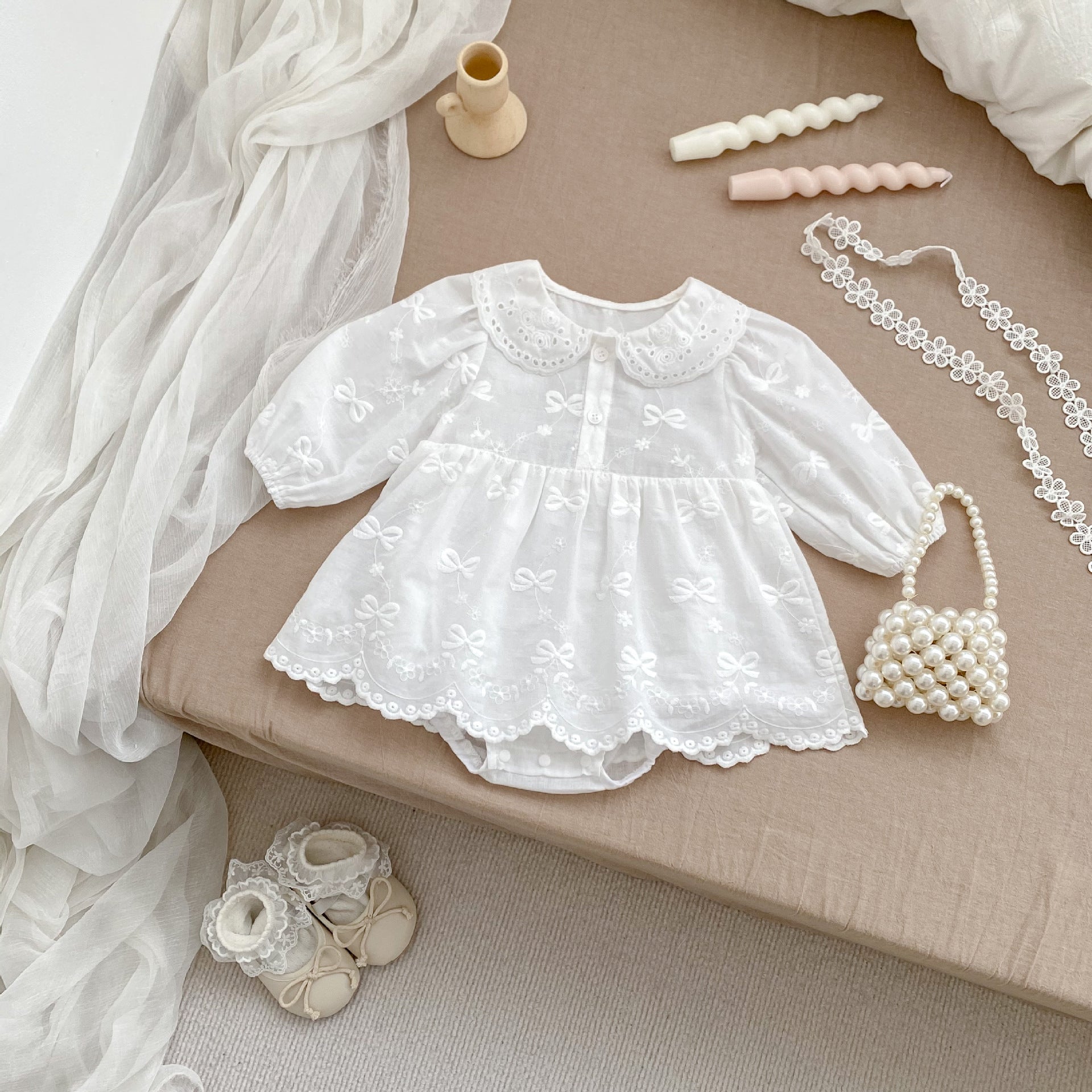 A beige long-sleeve dress for baby girls featuring embroidered bows and flowers, made from soft cotton, suitable for spring and autumn.
