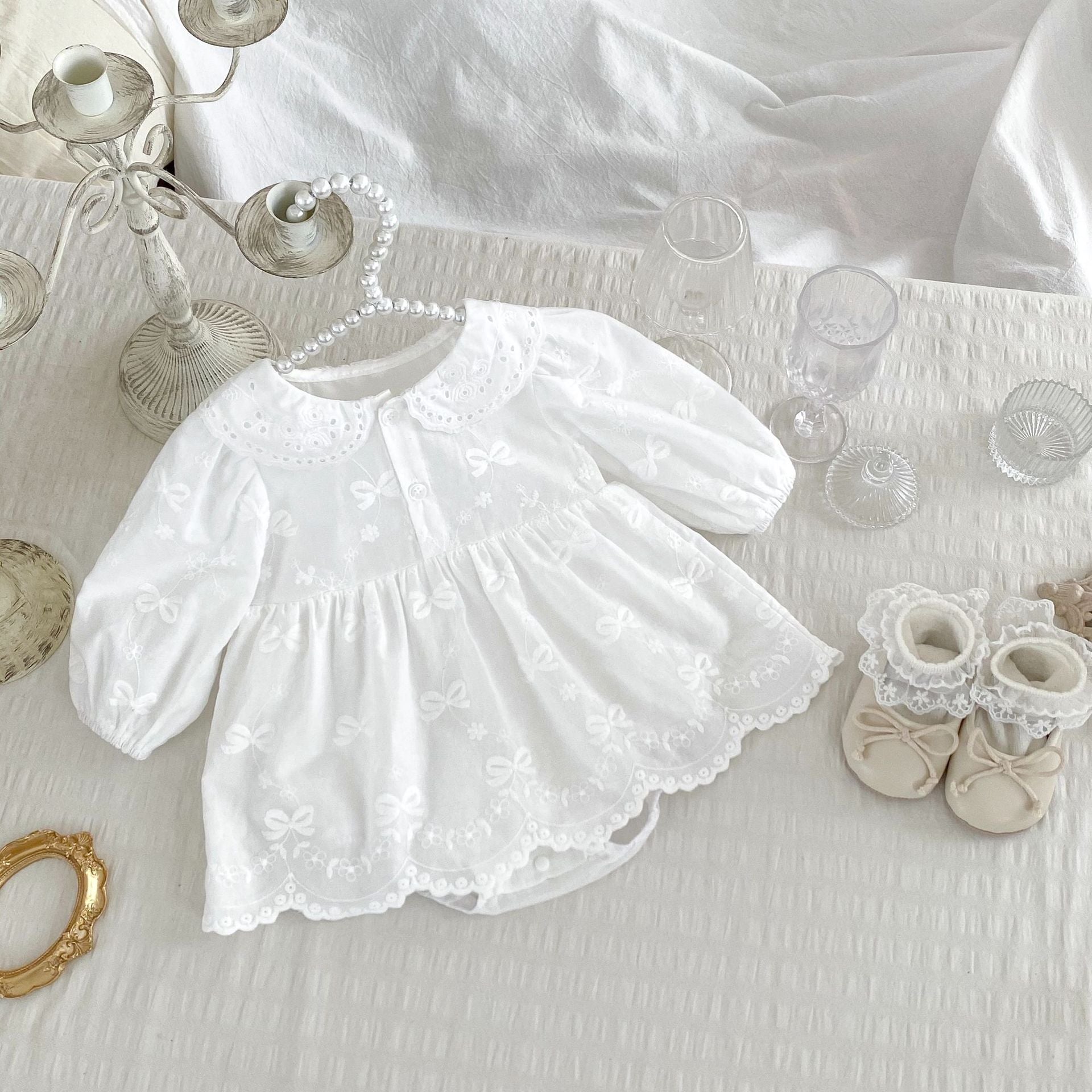 A beige long-sleeve dress for baby girls featuring embroidered bows and flowers, made from soft cotton, suitable for spring and autumn.