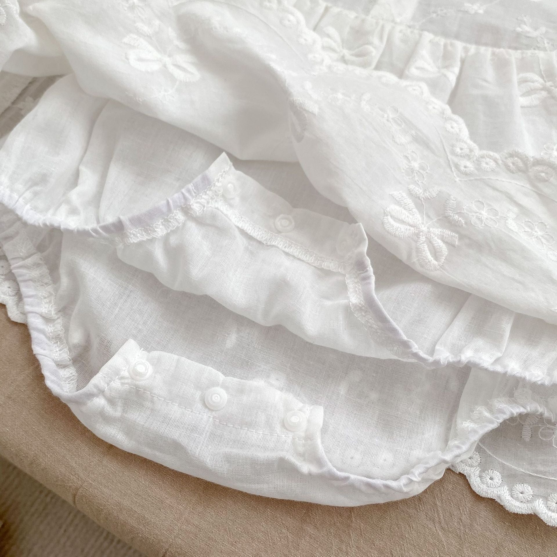 A beige long-sleeve dress for baby girls featuring embroidered bows and flowers, made from soft cotton, suitable for spring and autumn.