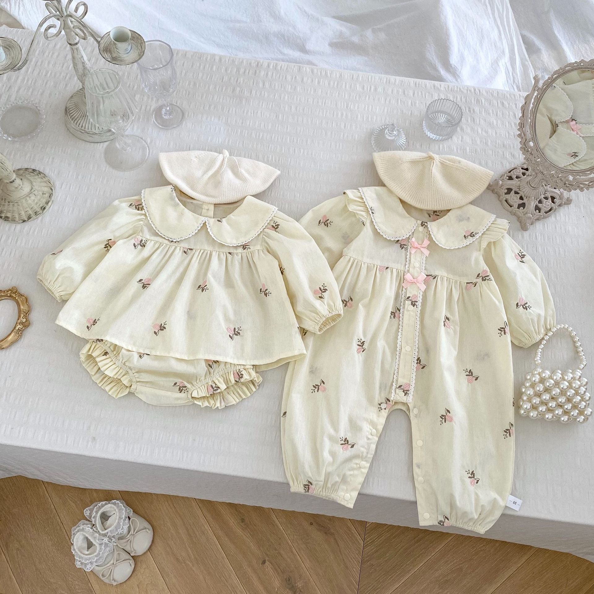 A cute baby girl wearing a floral print romper with long sleeves in beige and apricot colors, perfect for spring and autumn.