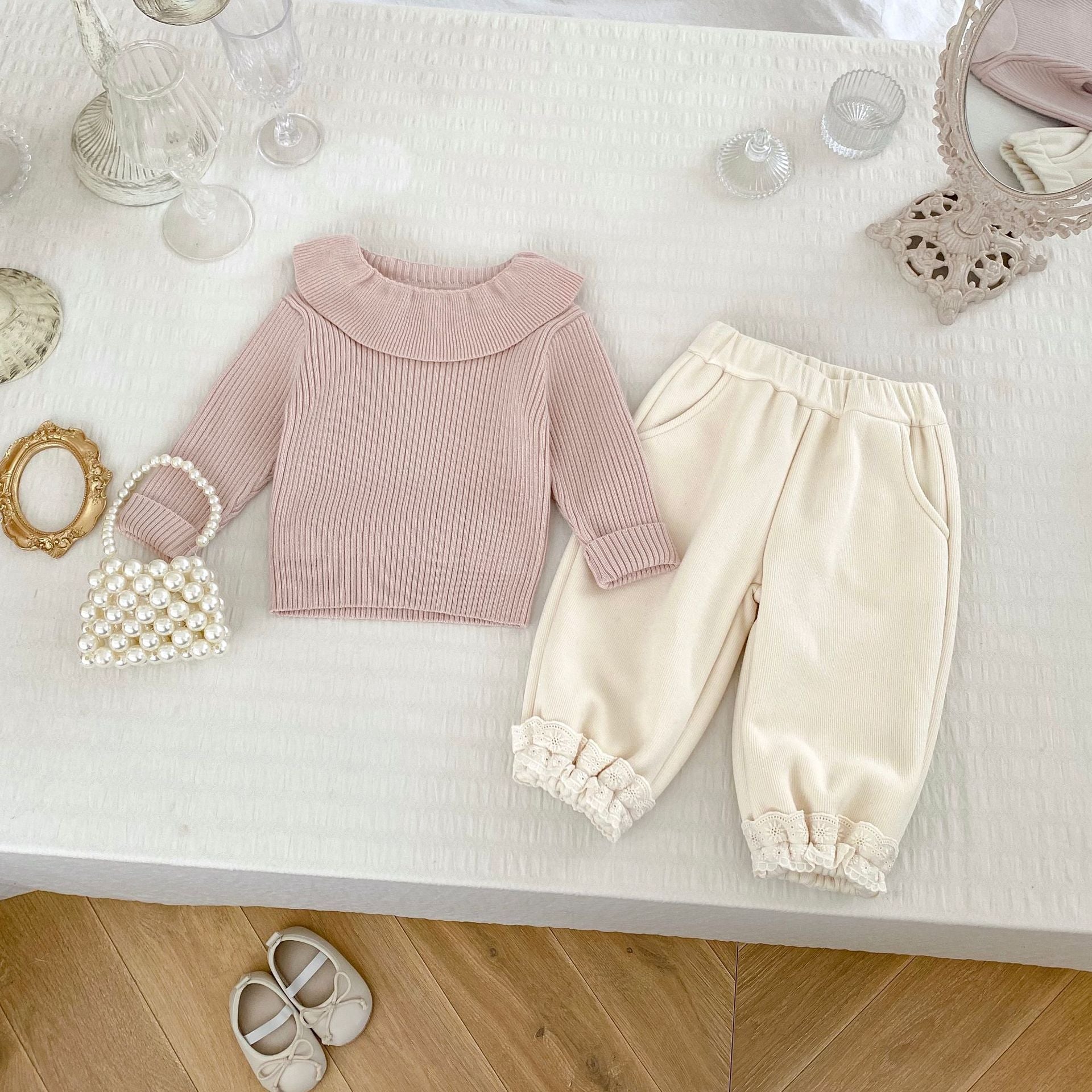 A soft cotton blend knitted top for baby girls, featuring long sleeves and available in white, pink, light pink, and beige.