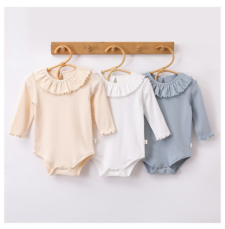 A collection of baby girls' solid color onesies in white, blue, and apricot, made from soft cotton fabric.