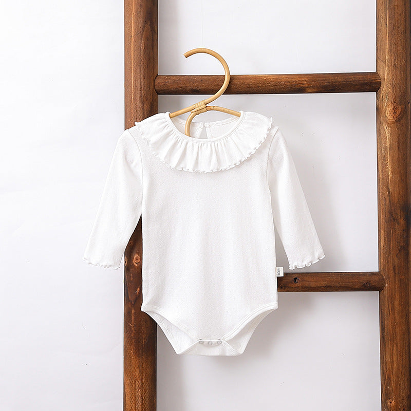 A collection of baby girls' solid color onesies in white, blue, and apricot, made from soft cotton fabric.