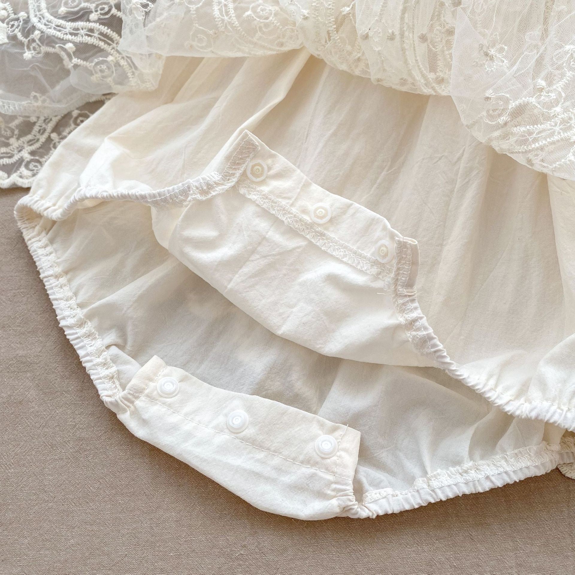 A stylish apricot onesies dress for baby girls featuring a mesh patched design, perfect for autumn wear.