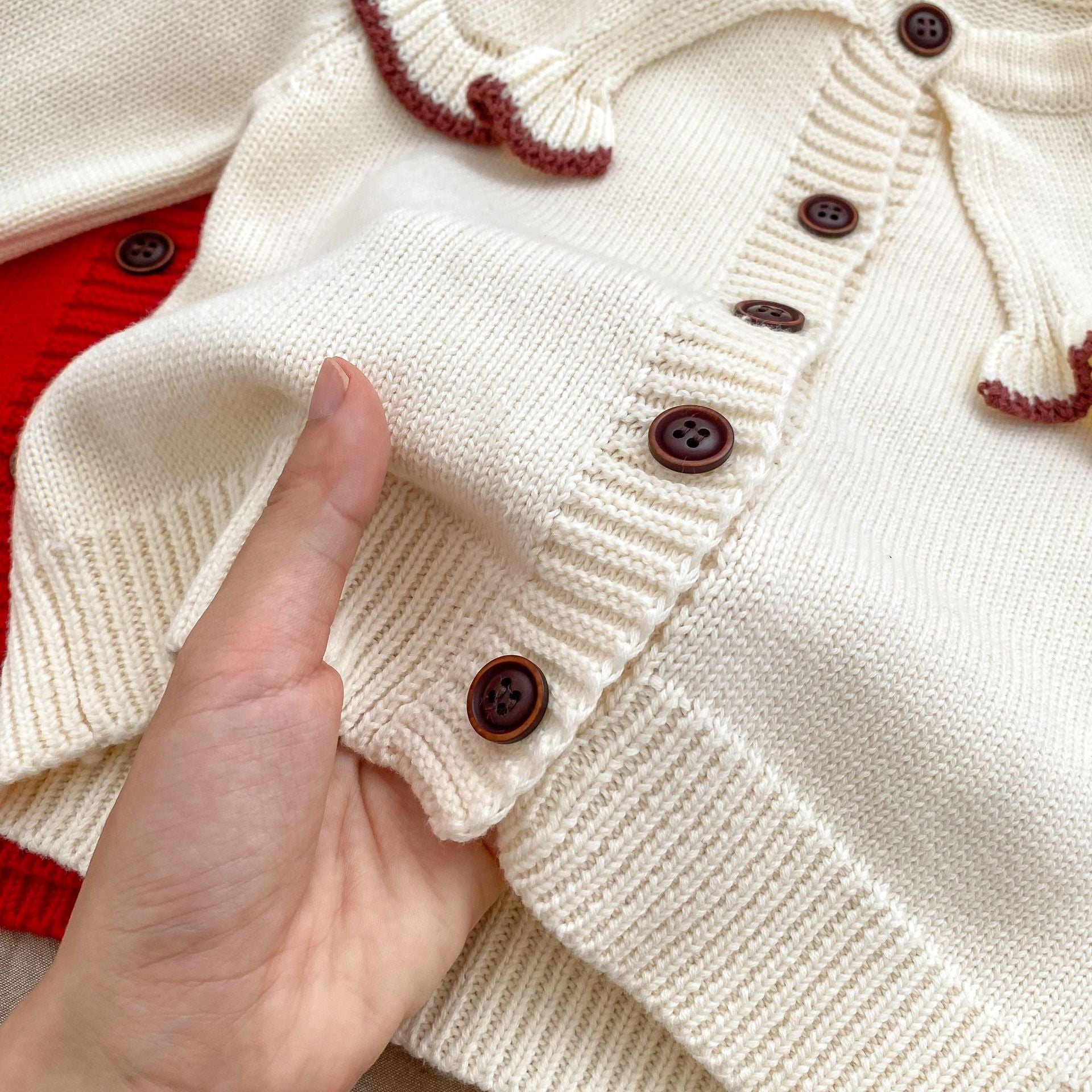 A cozy Autumn Vintage Style Knitted Cardigan for Baby Girl in red and beige, featuring floral and plain patterns, perfect for chilly weather.