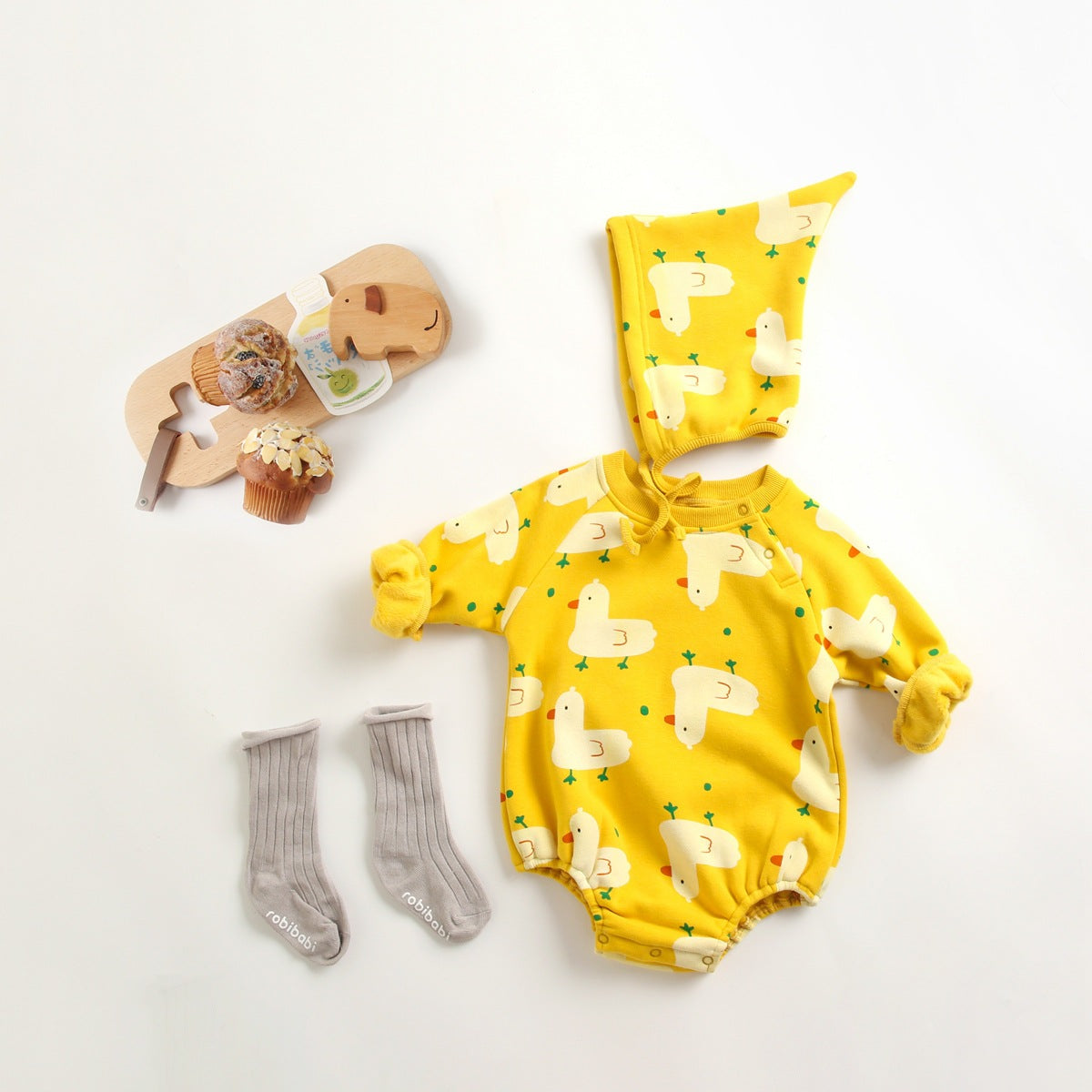 Baby wearing a cute cartoon duck print romper with matching hat, showcasing vibrant colors and playful design.