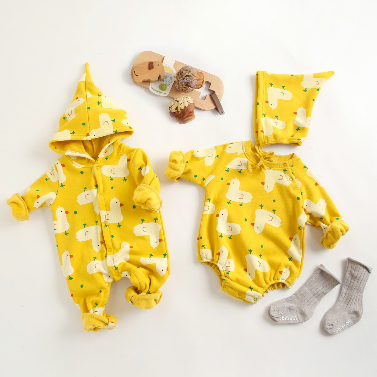Baby wearing a cute cartoon duck print romper with matching hat, showcasing vibrant colors and playful design.
