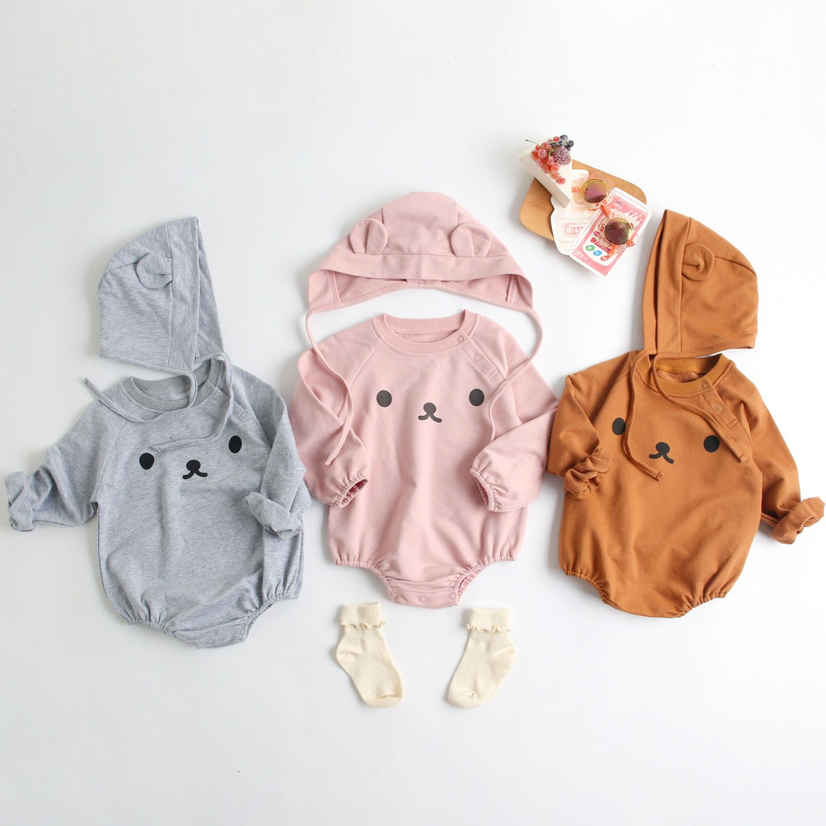 Baby wearing a long-sleeved cartoon print cotton onesie with a matching hat, showcasing a playful design in pink, grey, and brown colors.