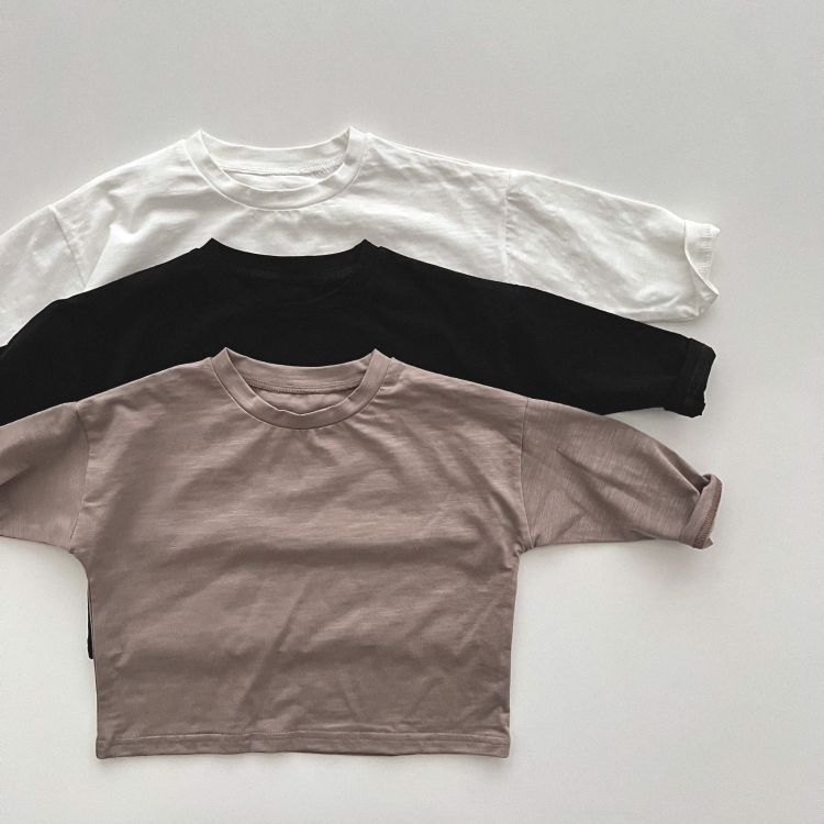 Baby boy and girl solid color pullover tops in white, black, and coffee, showcasing long sleeves and soft cotton fabric.
