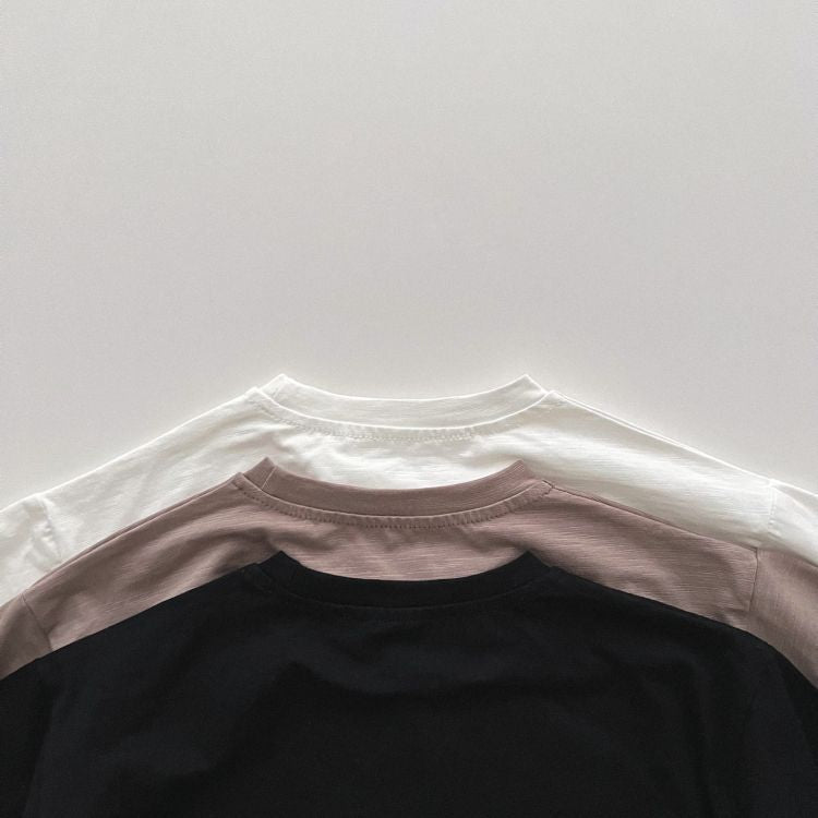 Baby boy and girl solid color pullover tops in white, black, and coffee, showcasing long sleeves and soft cotton fabric.