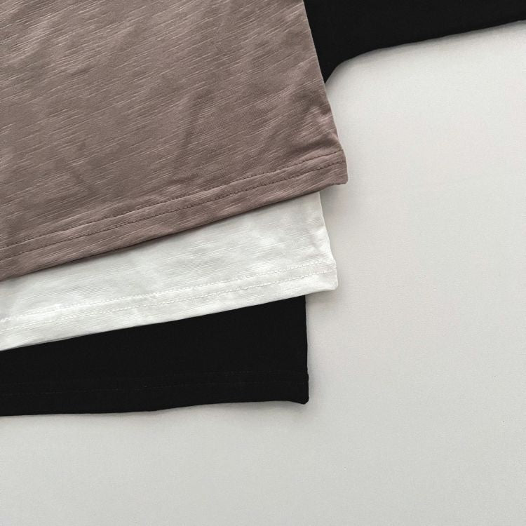 Baby boy and girl solid color pullover tops in white, black, and coffee, showcasing long sleeves and soft cotton fabric.