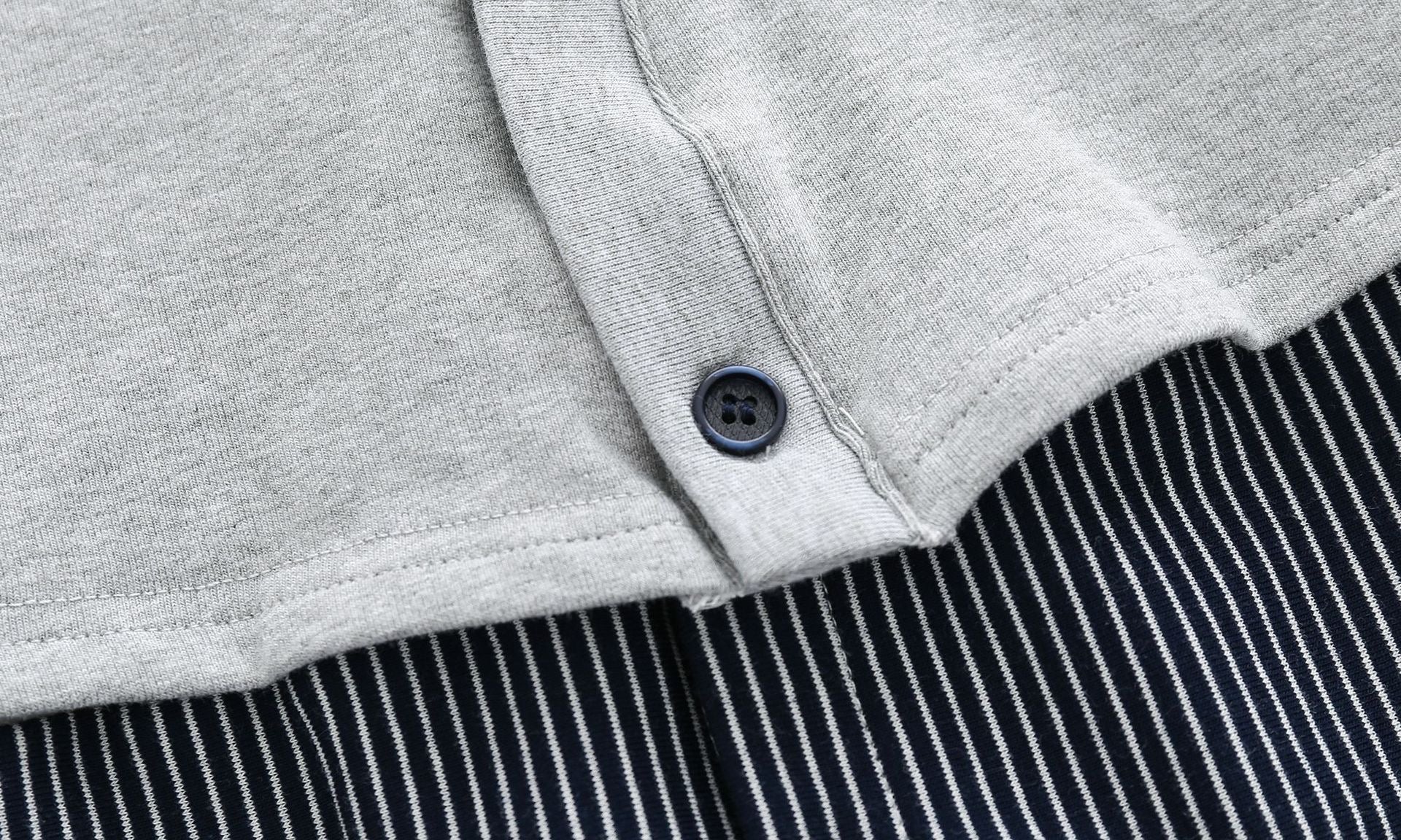 Baby boy wearing a stylish grey striped romper with badge patch and bow tie, showcasing a snap button front design.