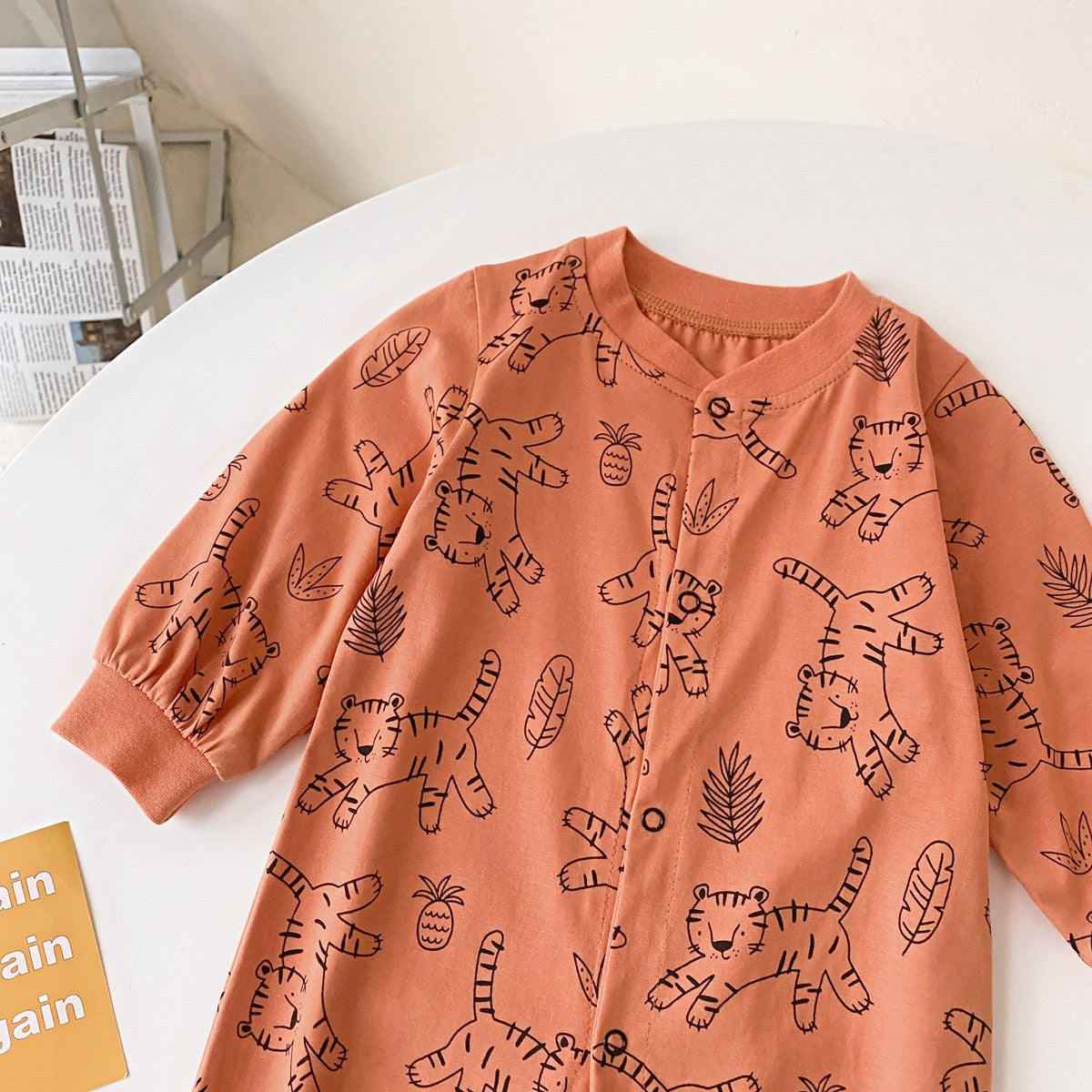 Baby boy wearing a long-sleeved jumpsuit with cartoon animal graphics and snap button front design, showcasing vibrant colors.