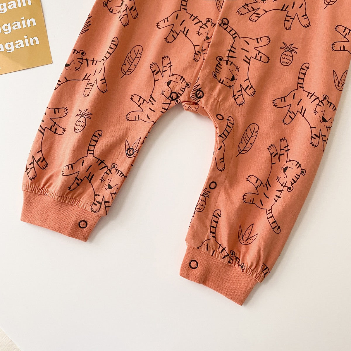 Baby boy wearing a long-sleeved jumpsuit with cartoon animal graphics and snap button front design, showcasing vibrant colors.