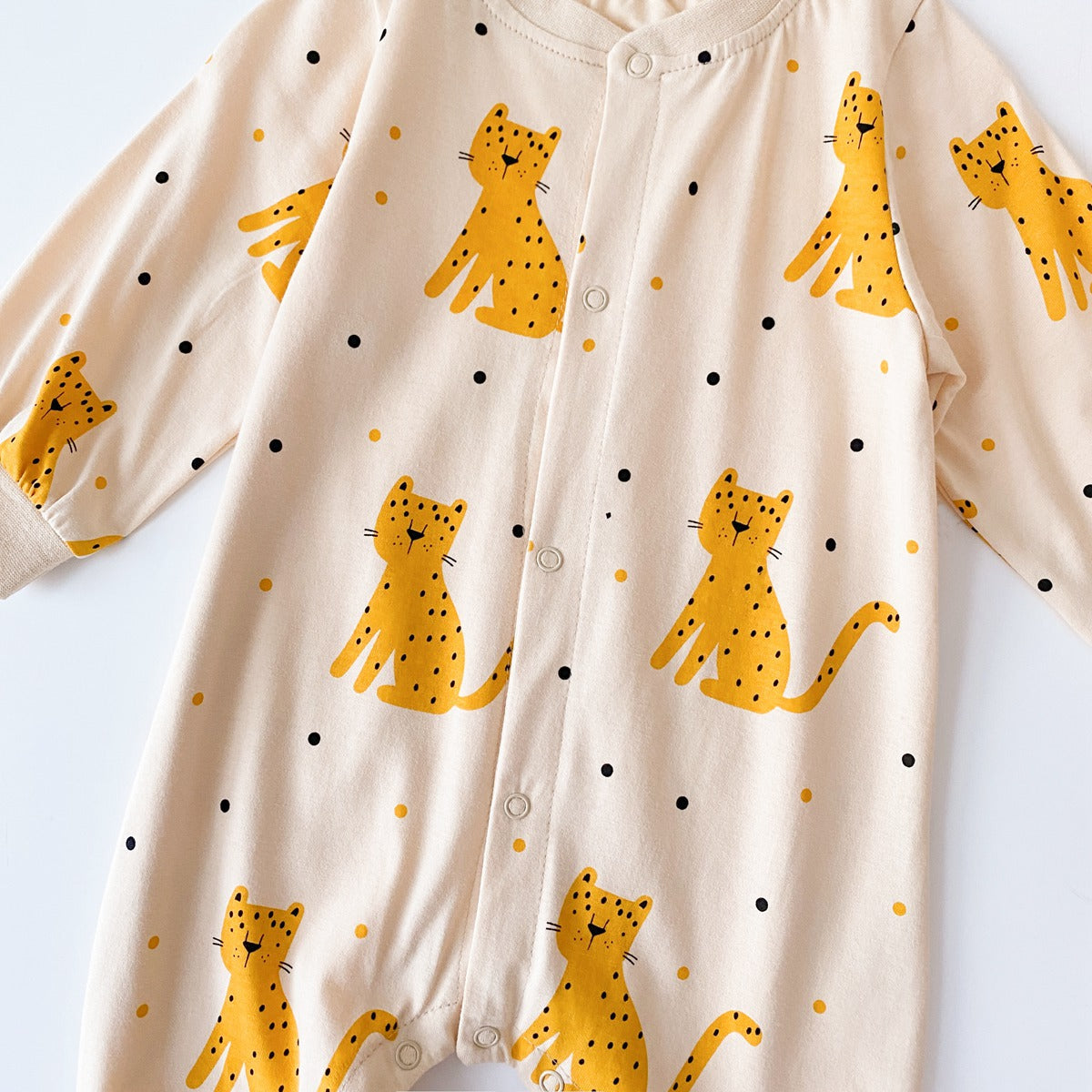 Baby boy wearing a long-sleeved jumpsuit with cartoon animal graphics and snap button front design, showcasing vibrant colors.