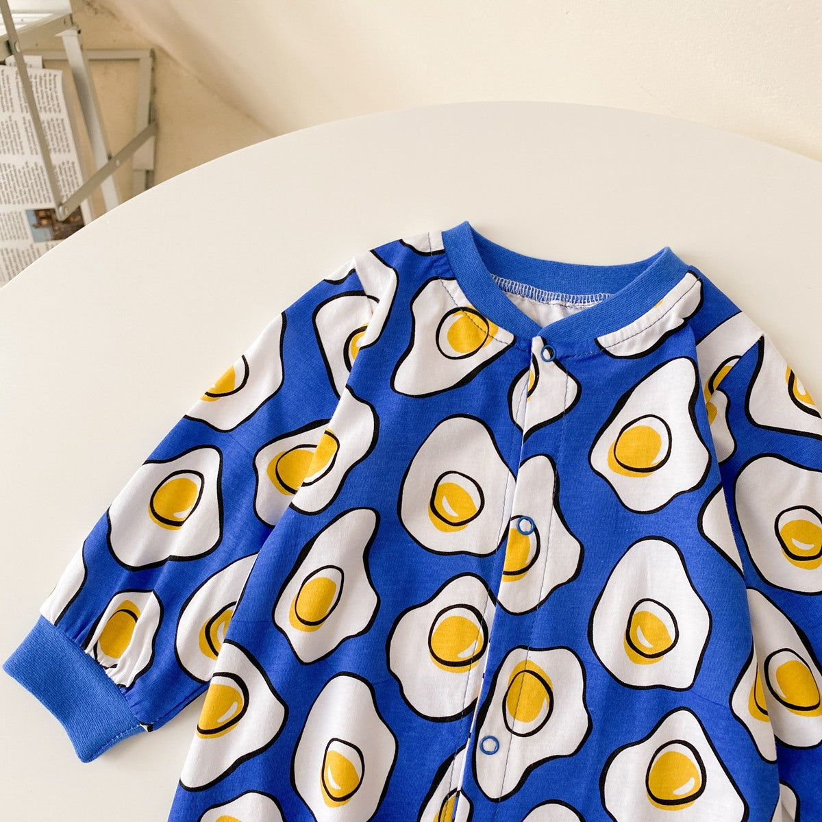 Baby boy wearing a long-sleeved jumpsuit with cartoon animal graphics and snap button front design, showcasing vibrant colors.