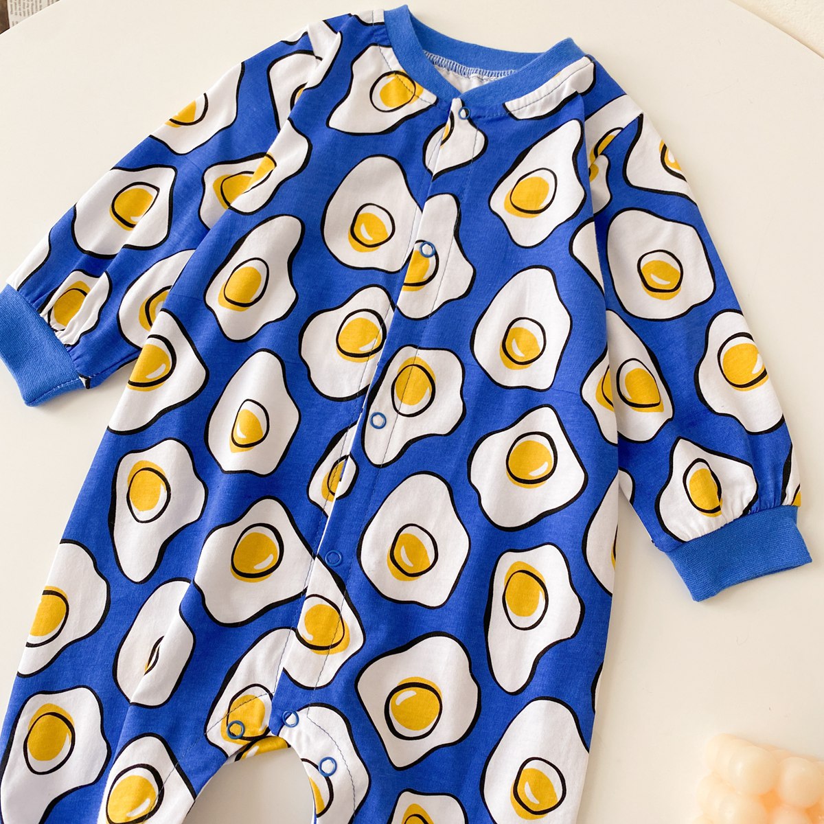 Baby boy wearing a long-sleeved jumpsuit with cartoon animal graphics and snap button front design, showcasing vibrant colors.