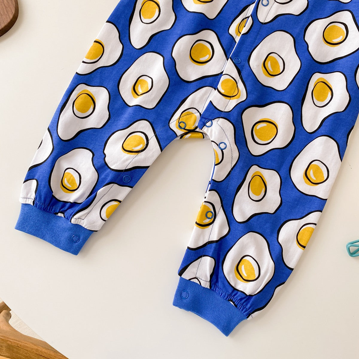 Baby boy wearing a long-sleeved jumpsuit with cartoon animal graphics and snap button front design, showcasing vibrant colors.