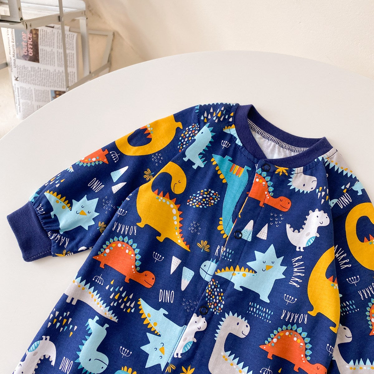 Baby boy wearing a long-sleeved jumpsuit with cartoon animal graphics and snap button front design, showcasing vibrant colors.