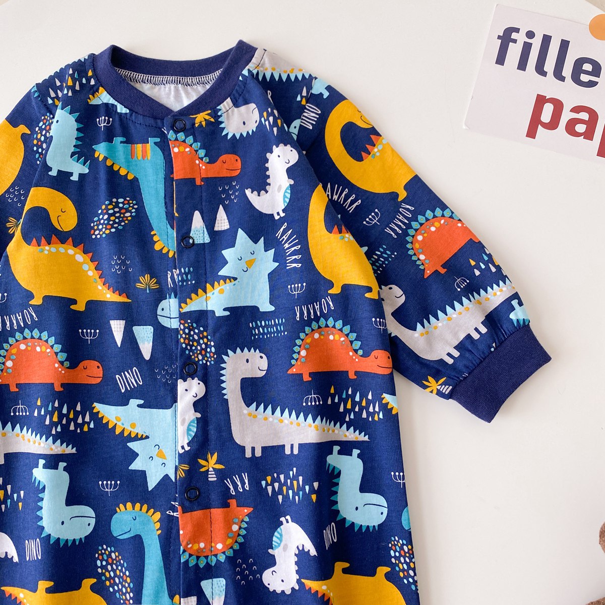 Baby boy wearing a long-sleeved jumpsuit with cartoon animal graphics and snap button front design, showcasing vibrant colors.