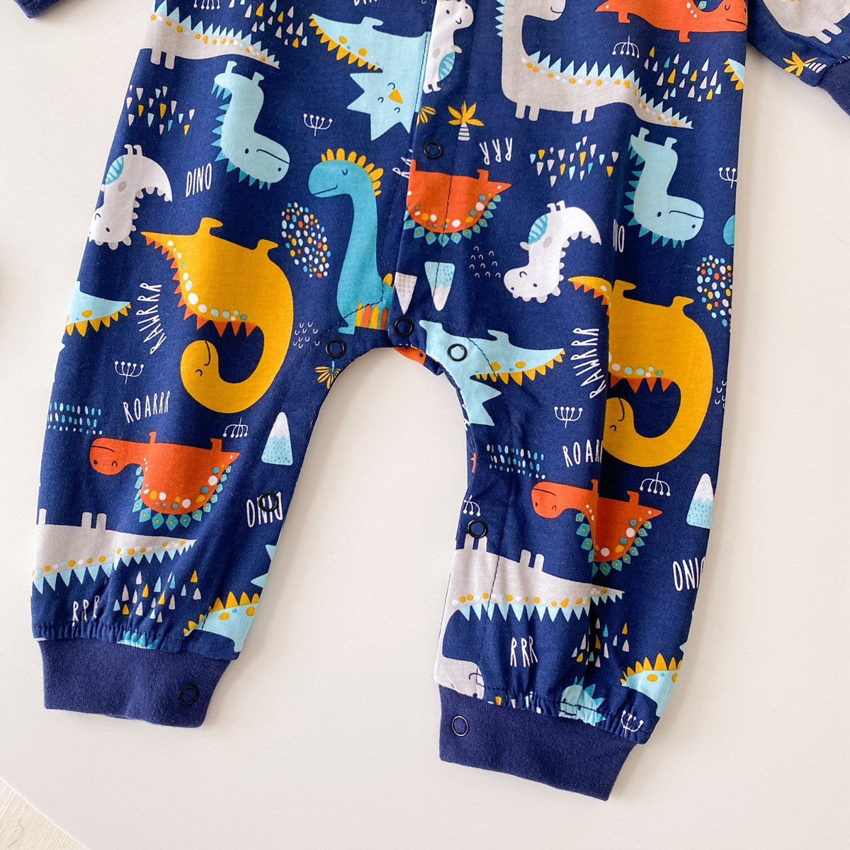 Baby boy wearing a long-sleeved jumpsuit with cartoon animal graphics and snap button front design, showcasing vibrant colors.