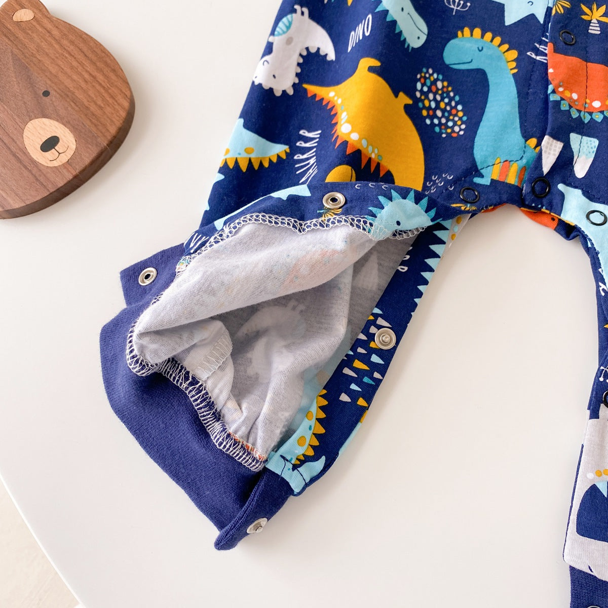 Baby boy wearing a long-sleeved jumpsuit with cartoon animal graphics and snap button front design, showcasing vibrant colors.