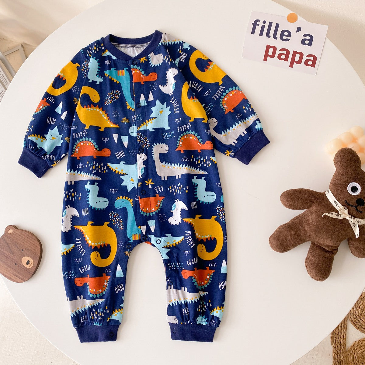 Baby boy wearing a long-sleeved jumpsuit with cartoon animal graphics and snap button front design, showcasing vibrant colors.