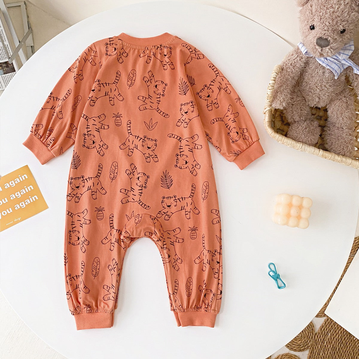 Baby boy wearing a long-sleeved jumpsuit with cartoon animal graphics and snap button front design, showcasing vibrant colors.