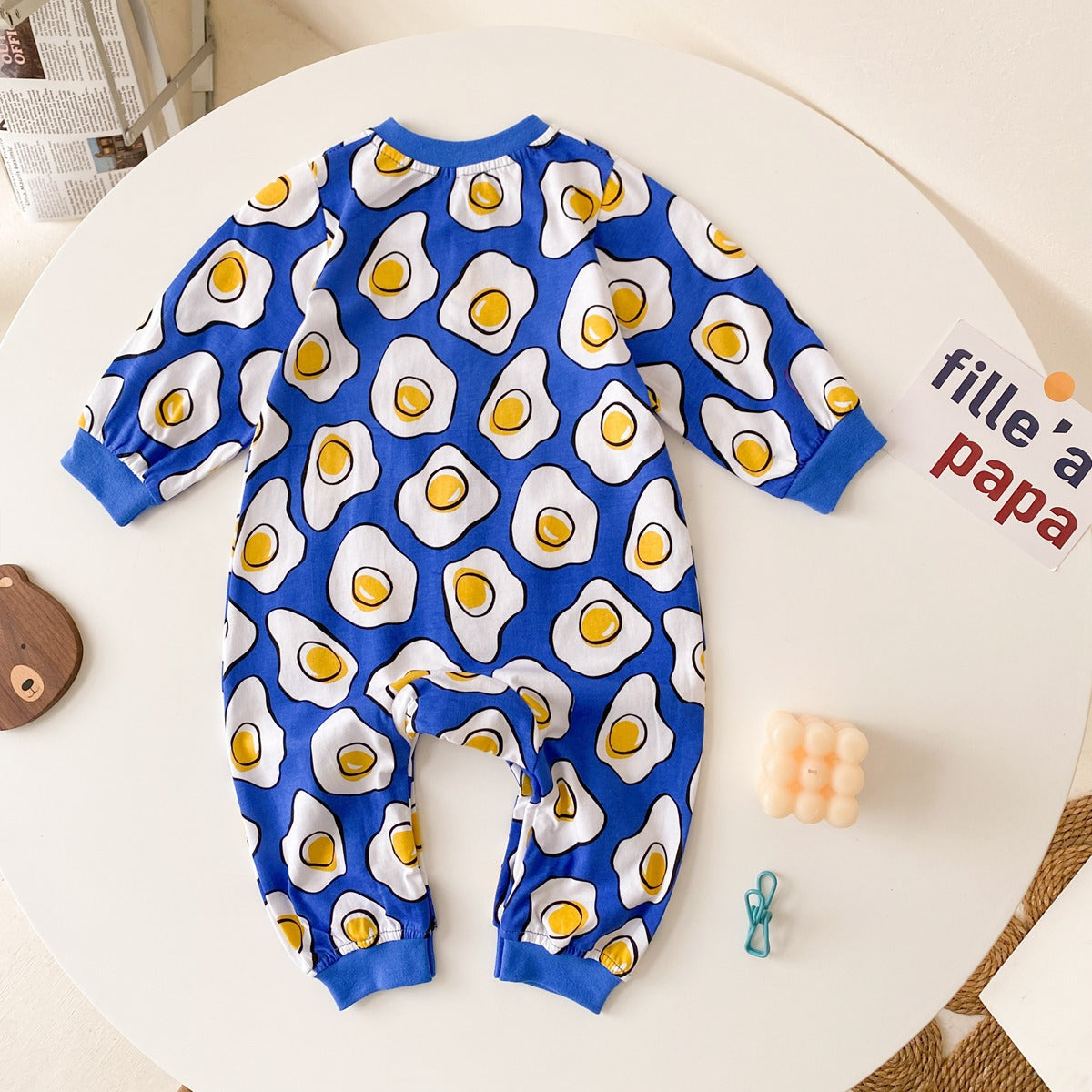 Baby boy wearing a long-sleeved jumpsuit with cartoon animal graphics and snap button front design, showcasing vibrant colors.