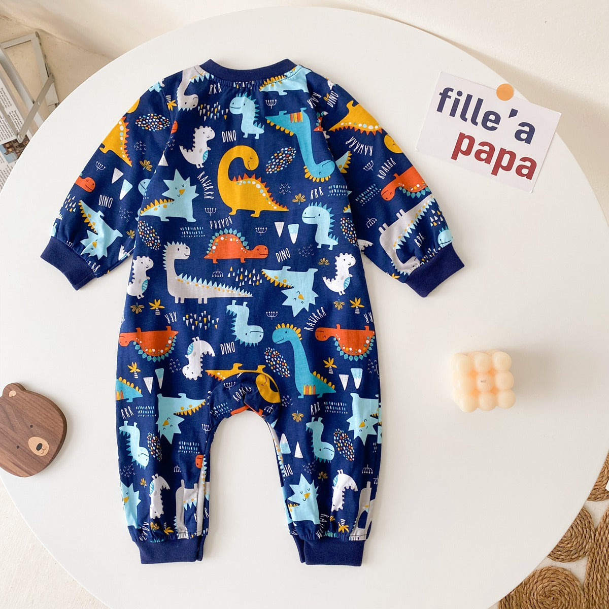 Baby boy wearing a long-sleeved jumpsuit with cartoon animal graphics and snap button front design, showcasing vibrant colors.