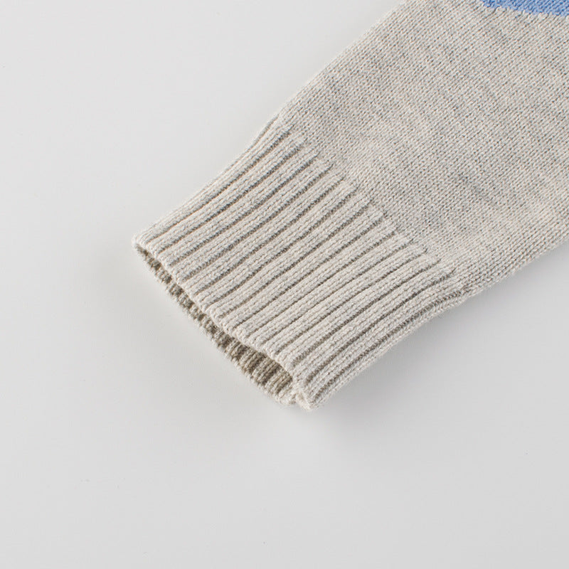 Baby boy wearing a cartoon dinosaur embroidered knitted sweater in blue, showcasing a playful design and cozy fit.