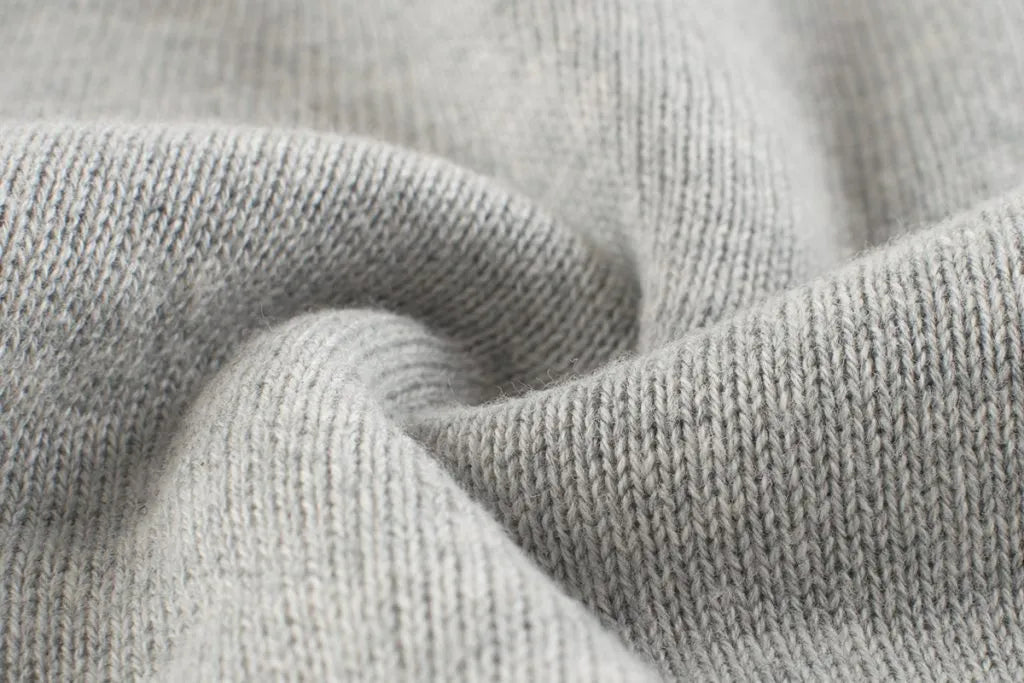 Baby boy wearing a cartoon dinosaur embroidered knitted sweater in blue, showcasing a playful design and cozy fit.