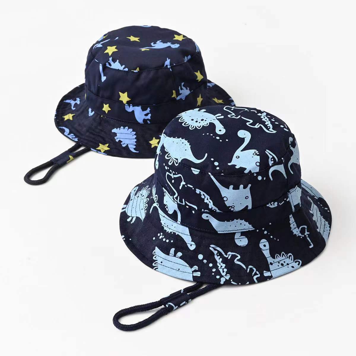 Baby boy wearing a cartoon dinosaur print bucket hat with a large brim, perfect for sun protection and stylish outdoor play.