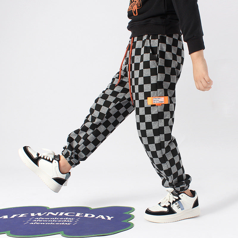 Baby boy wearing checkerboard print fleece thickened pants in black, showcasing warmth and style.