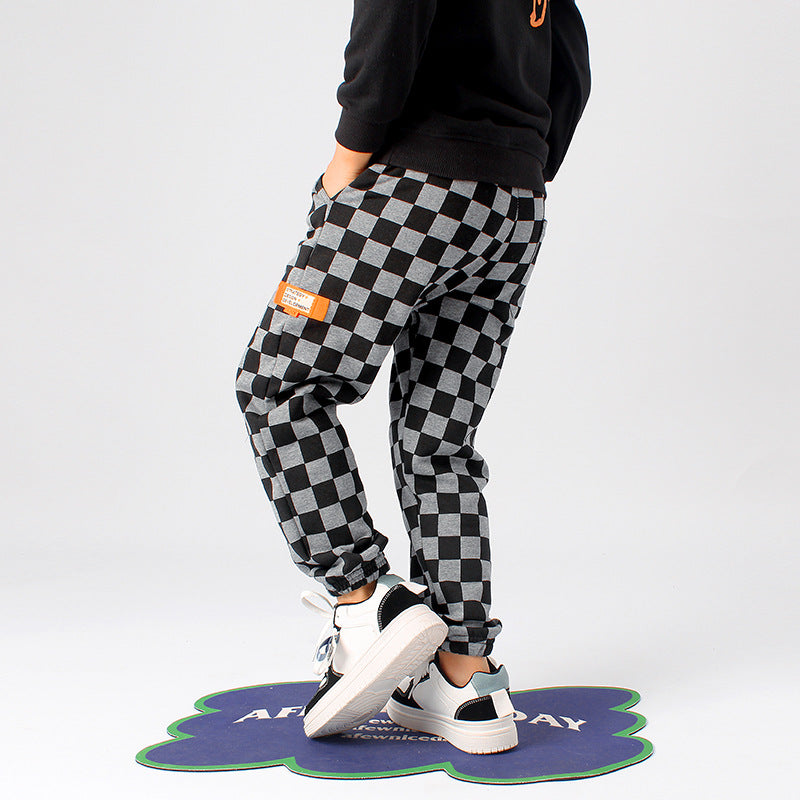 Baby boy wearing checkerboard print fleece thickened pants in black, showcasing warmth and style.