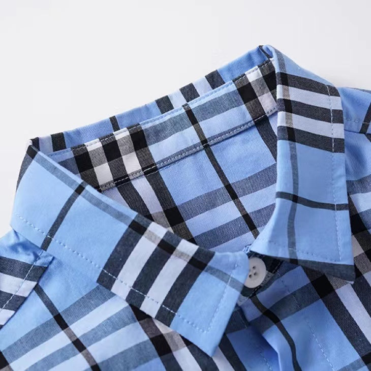 A stylish baby boy wearing a classic plaid pattern button front lapel shirt in red, green, and beige colors.