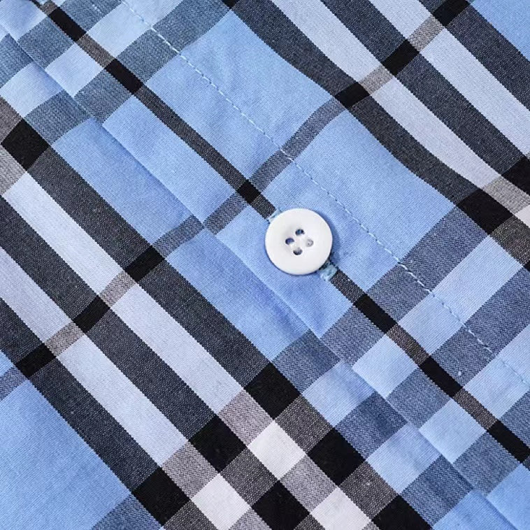 A stylish baby boy wearing a classic plaid pattern button front lapel shirt in red, green, and beige colors.