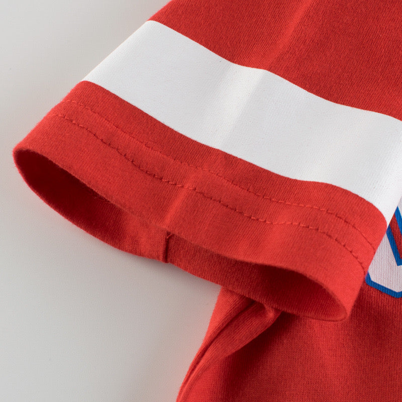 Baby boy wearing a colorful letters print short-sleeved t-shirt in white, red, and grey, perfect for summer outings.