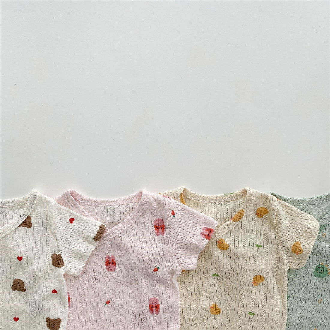 Baby girl wearing a soft cotton onesie with cartoon animal graphics in a vibrant color.