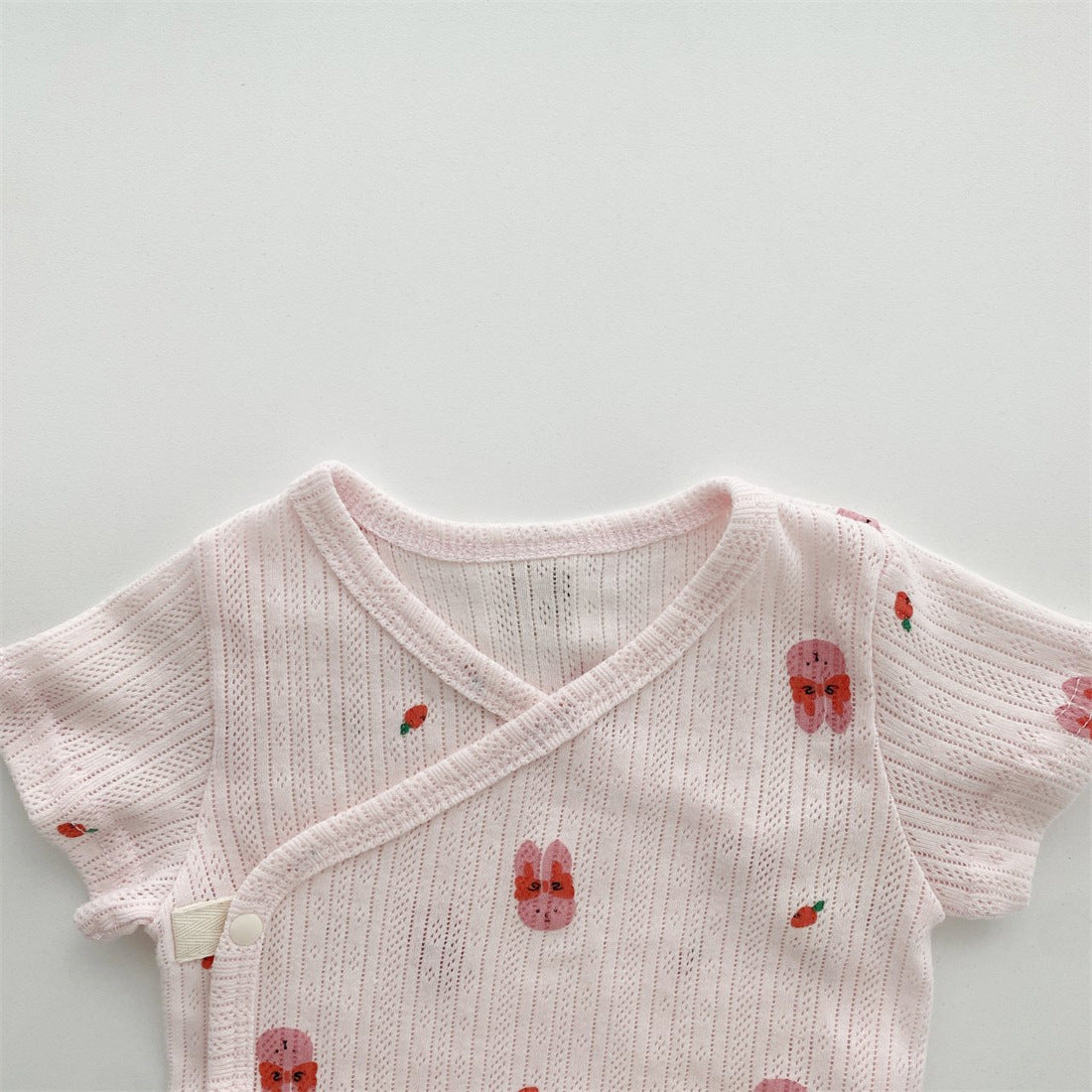 Baby girl wearing a soft cotton onesie with cartoon animal graphics in a vibrant color.