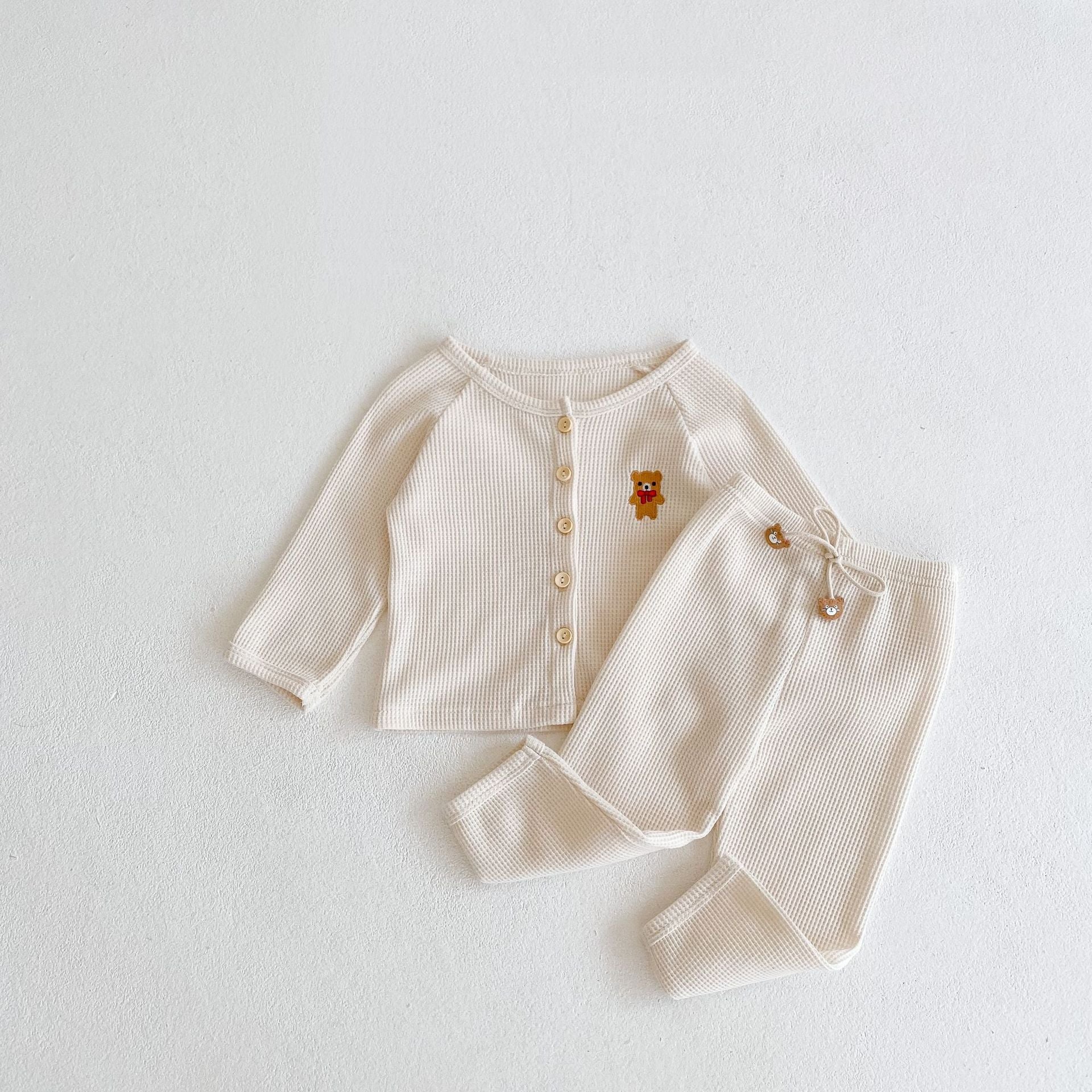 Baby outfit featuring a cartoon bear embroidery, waffle knitted cardigan, and combo pants in khaki and apricot colors.