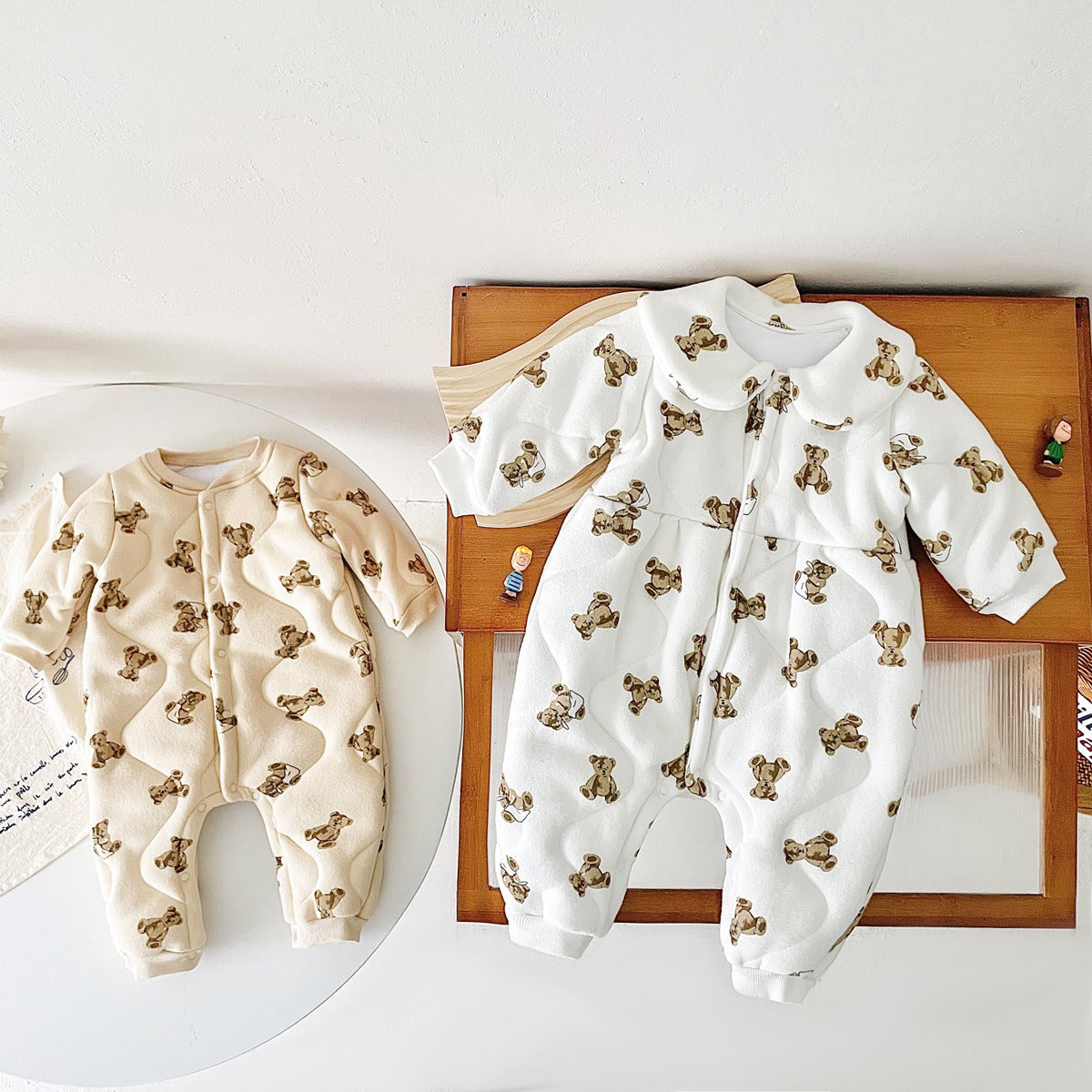 Baby wearing a thickened quilted winter romper with a cartoon bear print, showcasing a cozy and stylish design in white and apricot colors.