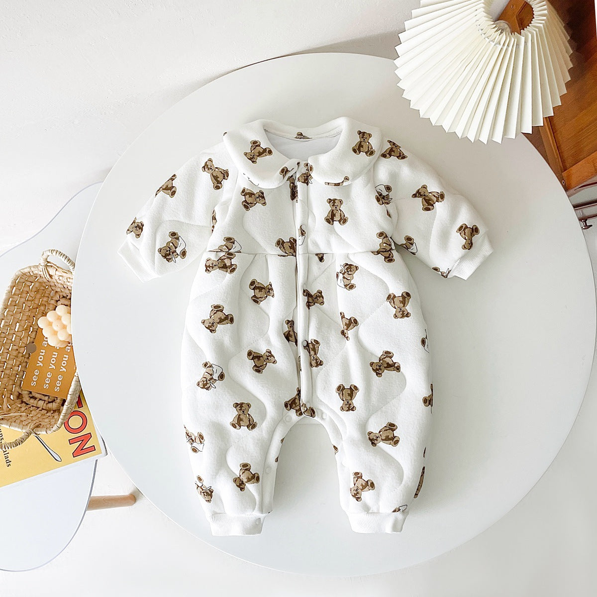 Baby wearing a thickened quilted winter romper with a cartoon bear print, showcasing a cozy and stylish design in white and apricot colors.