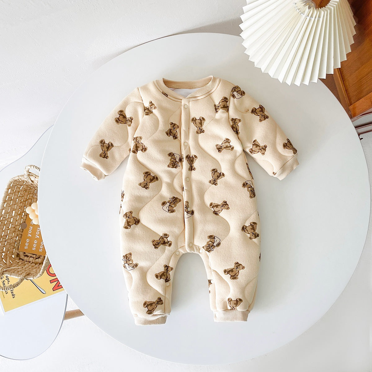 Baby wearing a thickened quilted winter romper with a cartoon bear print, showcasing a cozy and stylish design in white and apricot colors.